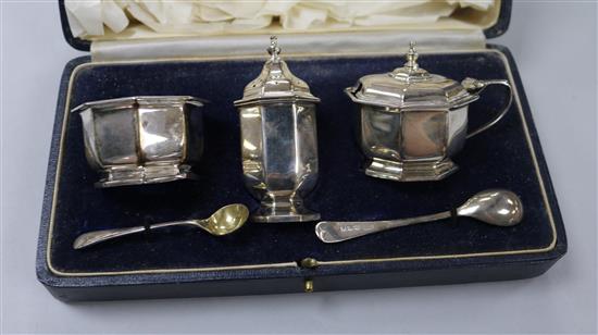 A cased silver three piece condiment set and two silver condiment spoons.